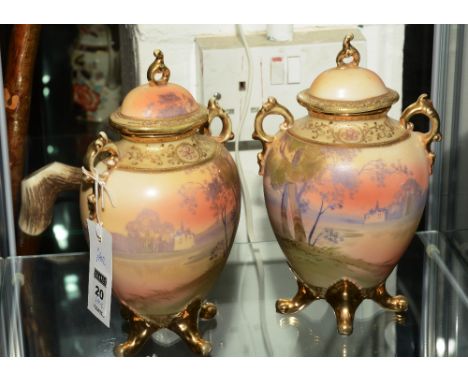 A pair of Noritake porcelain vases with covers, decorated with landscape scenes, on a green and gilt ground, 22cm high CONDIT