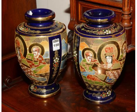 A pair of Satsuma ceramic vases, decorated with figures coloured in brown, green and orange, on a blue ground, 27cm high (2)