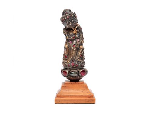 Bali, a silver togonan kris hilt, depicting a standing deity in court dress, set with semi-precious cabochons. H. 13 cm., mou