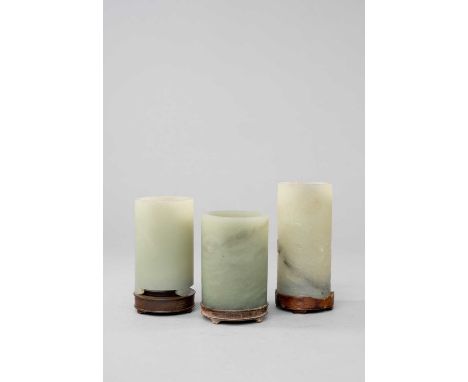 THREE CHINESE CELADON JADE BRUSHPOTS, BITONGQING DYNASTYAll of cylindrical form, the largest carved with two cranes amongst p