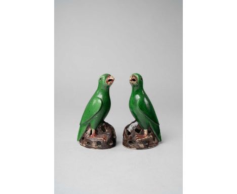A PAIR OF CHINESE GREEN-GLAZED BISCUIT MODELS OF PARROTS KANGXI 1662-1722Each looking up and standing on pierced rockwork, wi