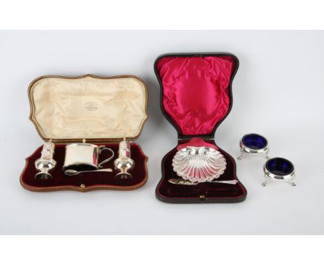 Cased silver shell butter dish and knife London 1904, cased set of two pepperettes and a mustard with spoon by Goldsmiths & S