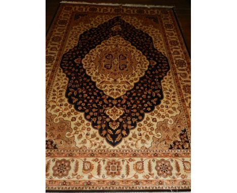 A Persian style blue ground Kum carpet, having quatrefoil medallion to centre on a floral ground, multi-bordered and fringed.