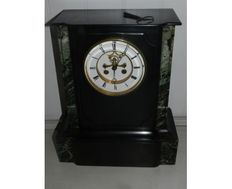 A late 19th century French black slate and green veriegated marble mantle clock, having a Roman enamelled dial and Brocot esc