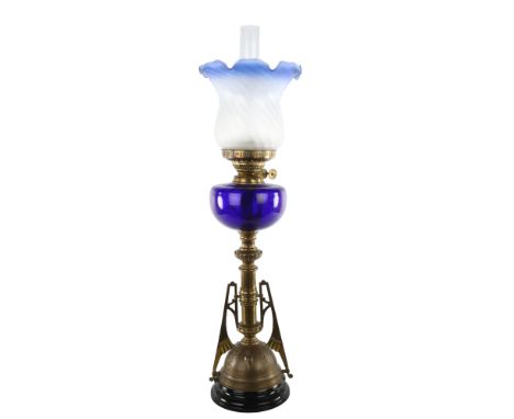 Victorian brass and blue glass duplex oil lamp, in the manner of Christopher Dresser, with embossed stork design to the base,