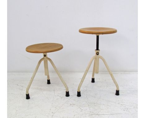 A pair of vintage height adjustable industrial stools, the tripod base made of painted tubular steel terminating to the origi