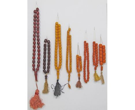 A collection of eight cherry amber / faturan type worry beads / kombologia / rosary. From left to right: [cherry amber - 156g