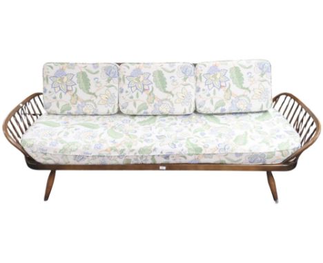 A mid 20th century Ercol dark stain elm and beech framed daybed with floral upholstered cushions flanked by railed ends on tu