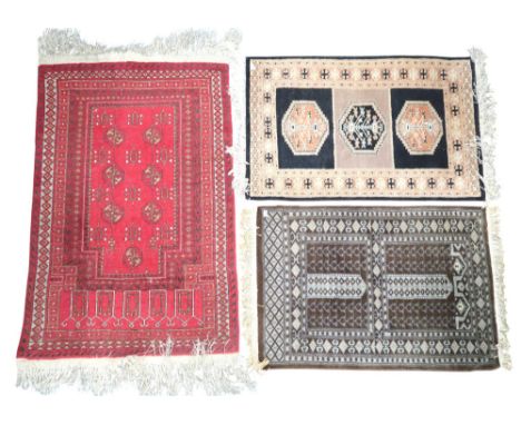A lot comprising a red ground Bokhara style prayer mat/rug with multiple borders, 122cm long x 79cm wide and two other assort