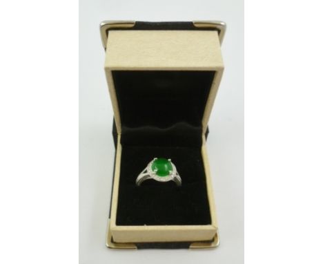 A RHODIUM FINISHED 18CT WHITE GOLD DRESS RING, set with central cabochon jade bordered by diamonds and split wire shank, ring