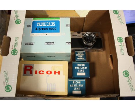 Cameras: a Yashica Lynx-5000 in makers box, a Ricoh 500 in makers box, a Ricohmate camera together with a set of Ricoh auxili