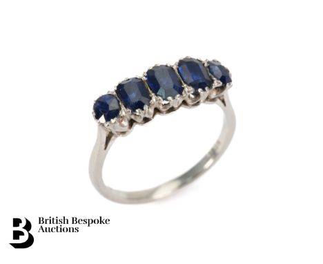 An antique 18ct white gold midnight blue sapphire ring, set with five graduated sapphires measuring approx. 5.3 x 3.8mm, two 