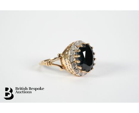 9ct Yellow gold sapphire and diamond ring. The ring set with an oval midnight blue sapphire measuring approx. 12 x 10mm, surr