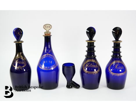 Four Georgian Bristol blue glass decanters and stoppers, comprising a pair of club shaped decanters each with a painted gilt 
