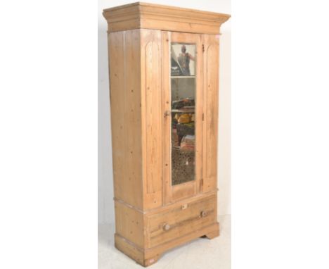 An early 20th Century scrubbed pine single wardrobe, single mirrored panel door over deep drawer, hanging rail to interior wi