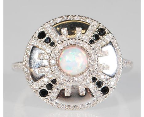 An impressive silver ring of round form set with a central opal having CZ's and black stones around. Stamped 925. Ring size R