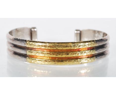 A stamped 950 open cuff silver bangle bracelet having a reeded design with hammered decoration and a central gold plated pane