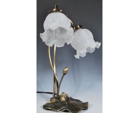 An Art Nouveau style table lamp having a naturalistic lily pad base with stems of scroll form and frosted glass flowerbud sha