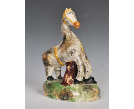 An early 19th Century Staffordshire ceramic figure of a horse and farrier with his dog, raised on a naturalistic base. Sponge