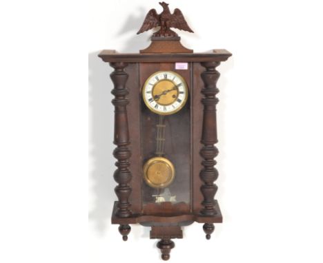 A 20th Century wooden cased Vienna regulator pendulum wall clock having glazed panels with a round face behind, having roman 