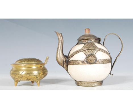 An antique oriental tea pot of small proportions having a white ceramic body with white metal embossed decoration mounts, lid