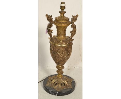 A large 20th Century twin handled gilt metal table lamp of urn shape form having pictorial relief decorated scenes with flora