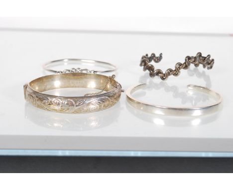 A selection of bangle bracelet to include an English hallmarked hinged bangle having engraved foliate decoration with a safet