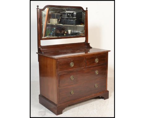An early 20th Century mahogany dressing chest having a swing mirror atop over flared top with three graduating drawers raised