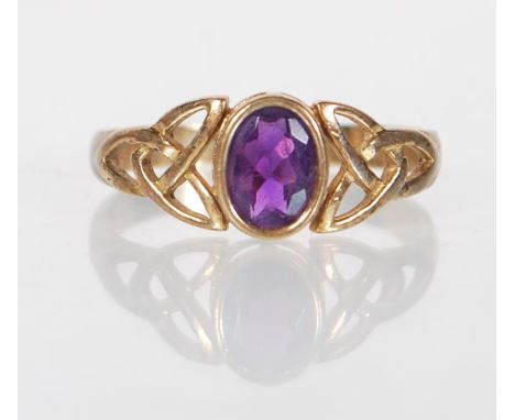 A hallmarked 9ct gold ring having an oval cut purple stone with celtic design pierced decoration shoulders. Hallmarked Sheffi