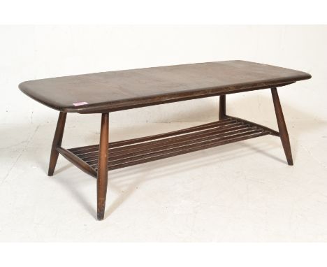 A retro 20th Century Ercol dark beech and elm coffee table raised on tapering supports united with slatted magazine undertier
