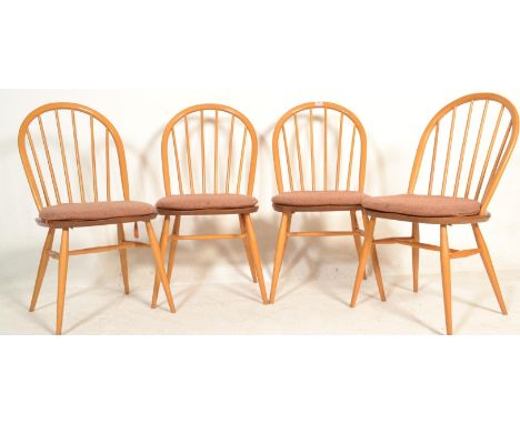 A set of four mid 20th century Ercol Windsor Quaker hoop-back dining chairs in light elm and beech construction being raised 