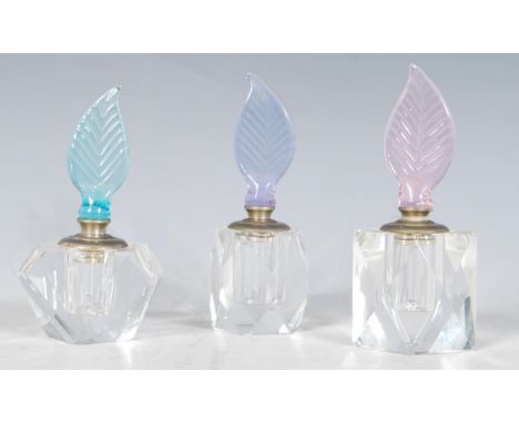 A group of three 20th Century Century faceted glass perfume bottles each having pastel coloured finial stoppers in the form o