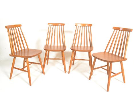 A set of four 20th Century vintage retro Ercol style spindle back dining chairs having shaped seats raised on turned tapering