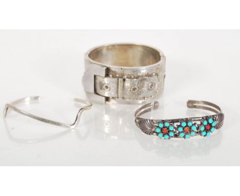 A group of three silver bangle bracelets to include a silver hallmarked hinged bangle with raised buckle decoration (hallmark