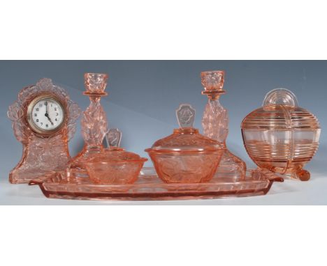 An early 20th Century Art Deco pink pressed glass dressing table set having impressed rose decoration to include tray, two ca