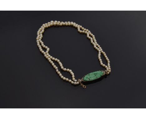 A graduated two row natural pearl necklace (not tested) with carved green jade and gold fastener, of 77 and 76 pearls from ap
