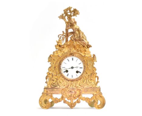 An ornate French ormolu mantel clock, c.1850, the white enamel dial with Roman numerals, within scrolling foliage, surmounted