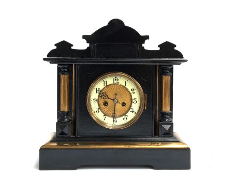 An ebonised mantel clock, dial with Arabic numerals, flanked by columns on either side 