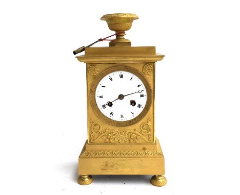 A gilt metal continental mantel clock, with urn finial, white enamelled dial, with roman numerals and outer minute track, wit