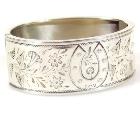 A Victorian silver bangle, of compressed oval outline with part engine turned floral decoration, Birmingham 1883, 7cm wide, 1