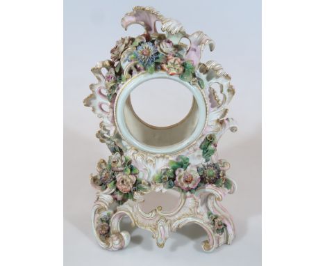 An early 20thC Continental porcelain clock case, heavily set with gilt highlighted scrolls, bisque flowers, etc, polychrome d