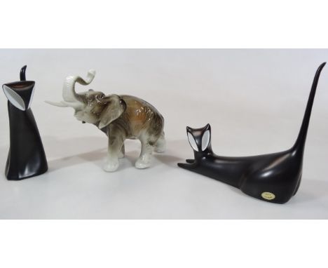 A 20thC Royal Dux pottery figure of an elephant, with trunk raised, 18cm high, and two Studio style Dux figures of cats in bl