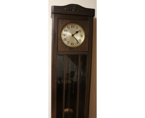 A mid 20thC long case clock, with silvered 24cm dia. Arabic dial with a stained beech case with glazed front revealing pendul
