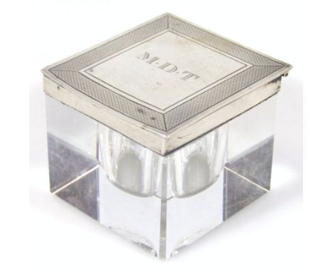 A mid 20thC silver and glass ink stand, the initialled top with an engine turned outline, hinging to reveal glass interior on