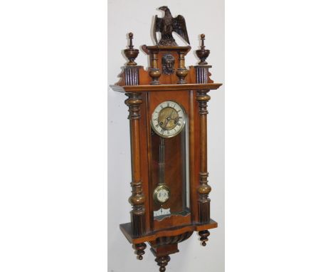 A late 19thC walnut cased Vienna wall clock, surmounted by an eagle finial with 14cm dia, dial flanked by quarter columns, re