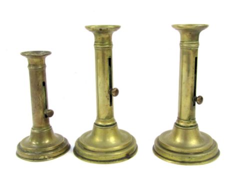 Three Victorian brass candle sticks, with lever candle adjustment, comprising a pair, 20cm high, and a single stick, 16cm hig