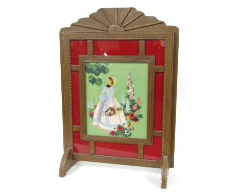 An Art Deco design fire screen, the embroidered centre depicting a crinoline lady carrying a  basket of flowers, in a red out