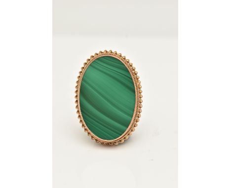 A 9CT GOLD MALACHITE BROOCH, a flat oval cut malachite, collet set in yellow gold with twist detail, approximate length 30mm,