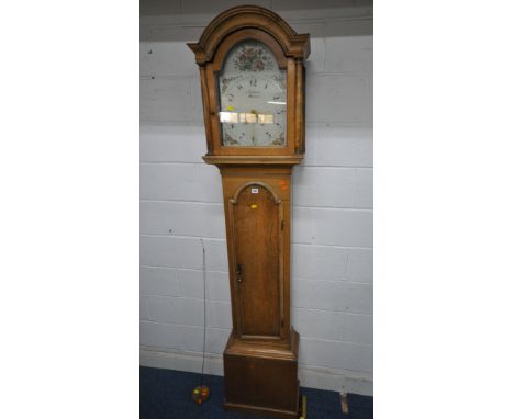 AN OAK CASED LONGCASE CLOCK, the arched hood with a glass door, that’s enclosing a 11.5 inch painted dial, depicting Arabic n