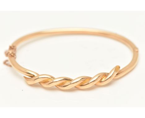 A YELLOW METAL HINGED BANGLE, twist detail on a polished hinged bangle, fitted with a push piece clasp and additional safety 
